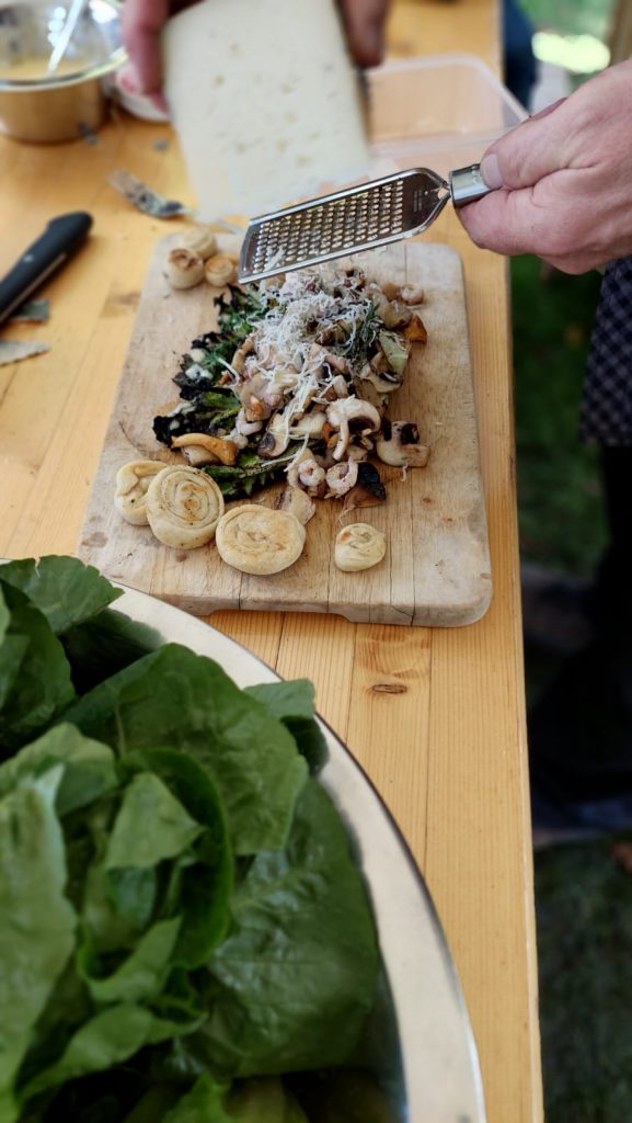 Käse wird über Salat und Pilze gerieben